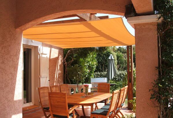 Voile d’ombrage respirante au-dessus d’une terrasse avec pergola